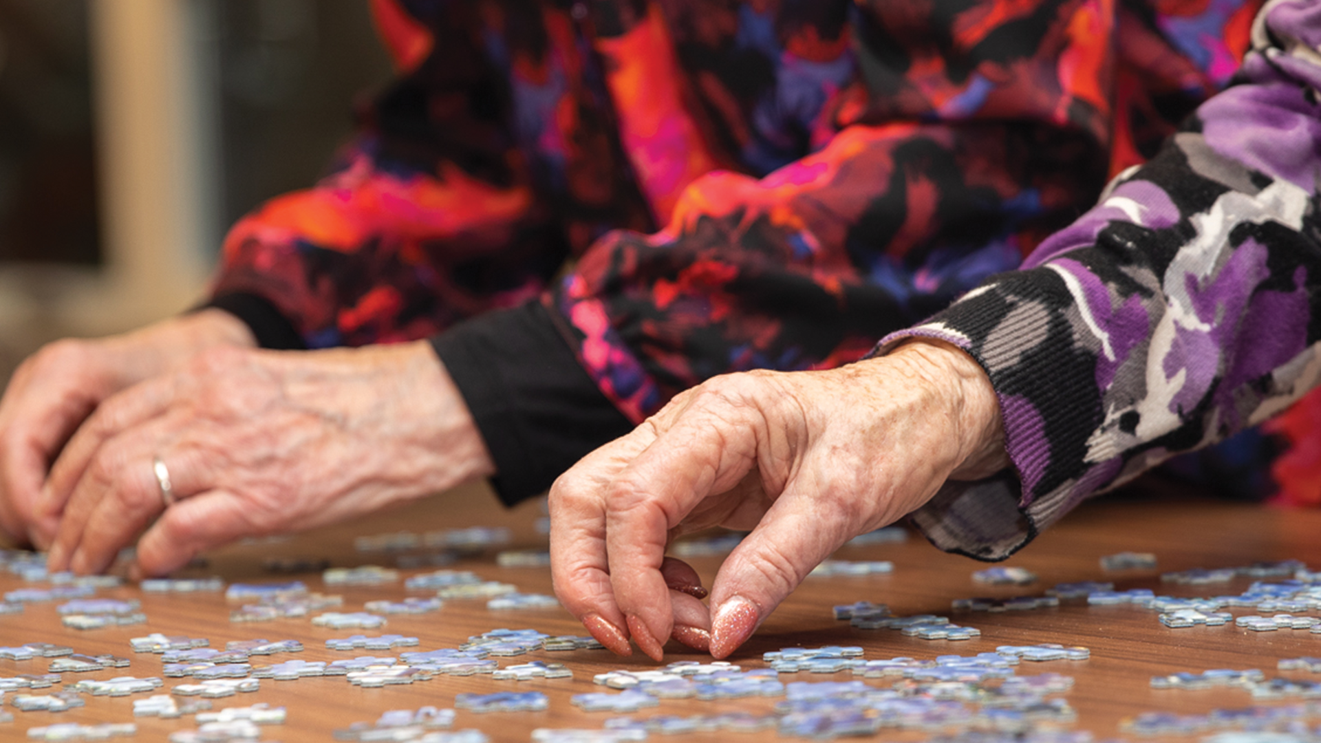 Hands of two elderly women doing a puzzle, a hobby for the elderly